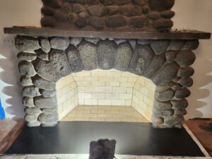 Stone fireplace under construction with a partially completed hearth and no mantle.