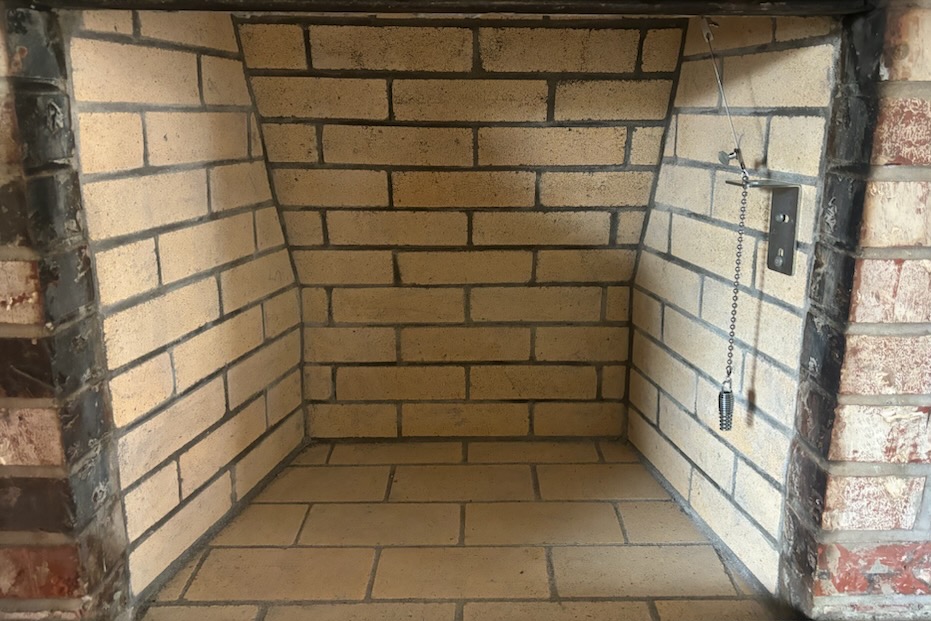 An empty brick built-in alcove with metal chains on the right side.