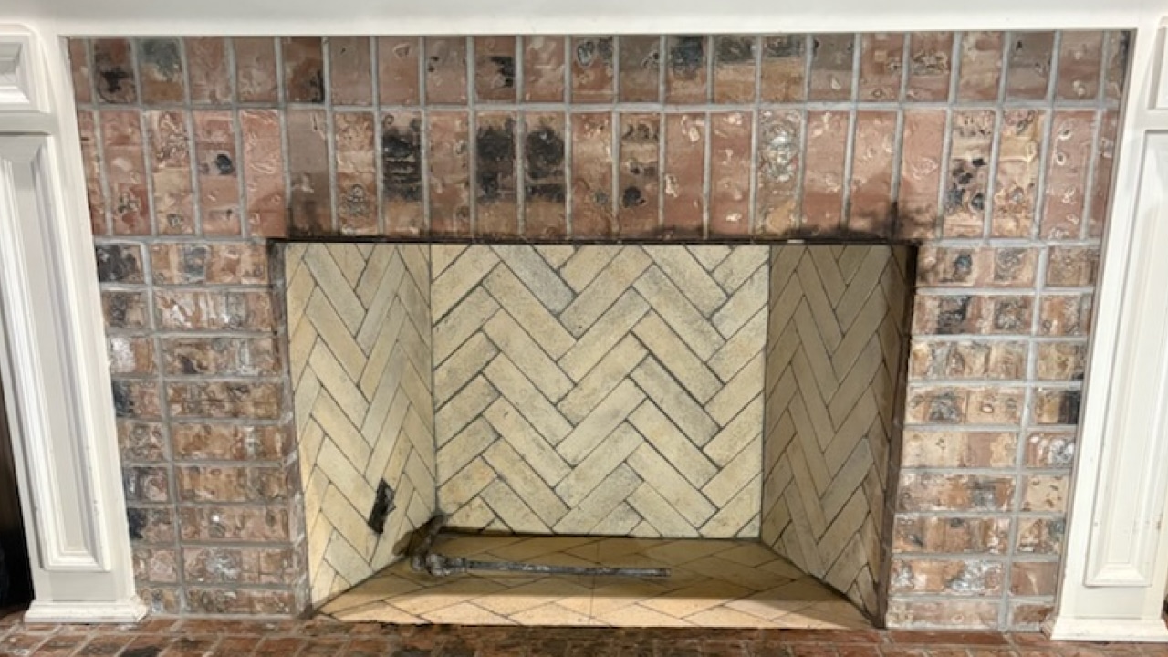 Brick fireplace with a herringbone-patterned interior. The exterior bricks are varied in color, mostly brown and red.